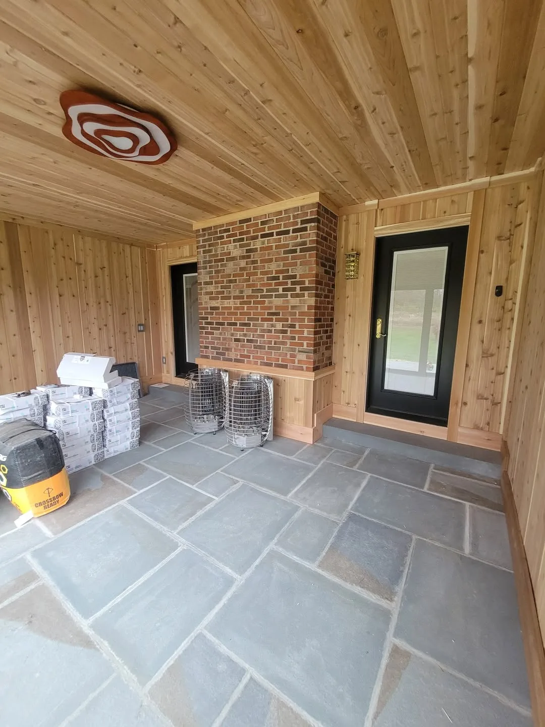 Interior clad in tongue-and-groove cedar with an exposed brick chimney breast and bluestone floor