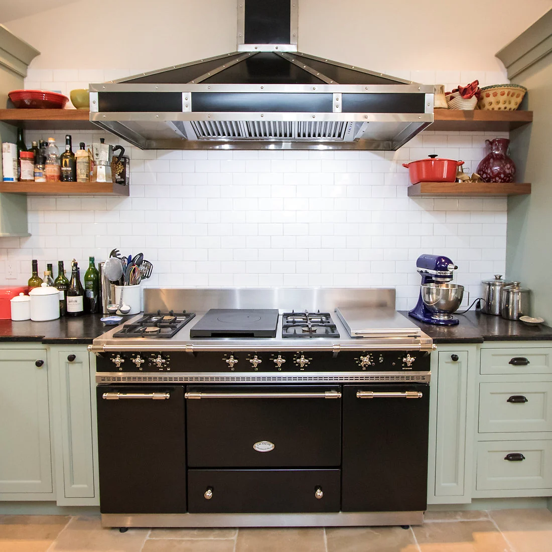 Black range hood with open wood shelving against a white subway-tile backsplash