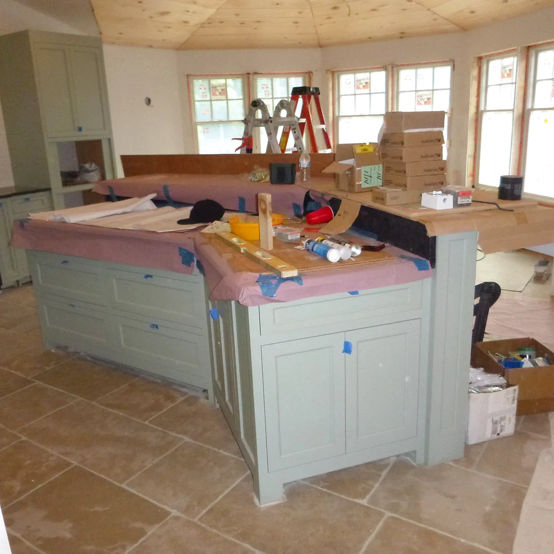 The same island mid-installation, cabinetry taped off and countertop template in place