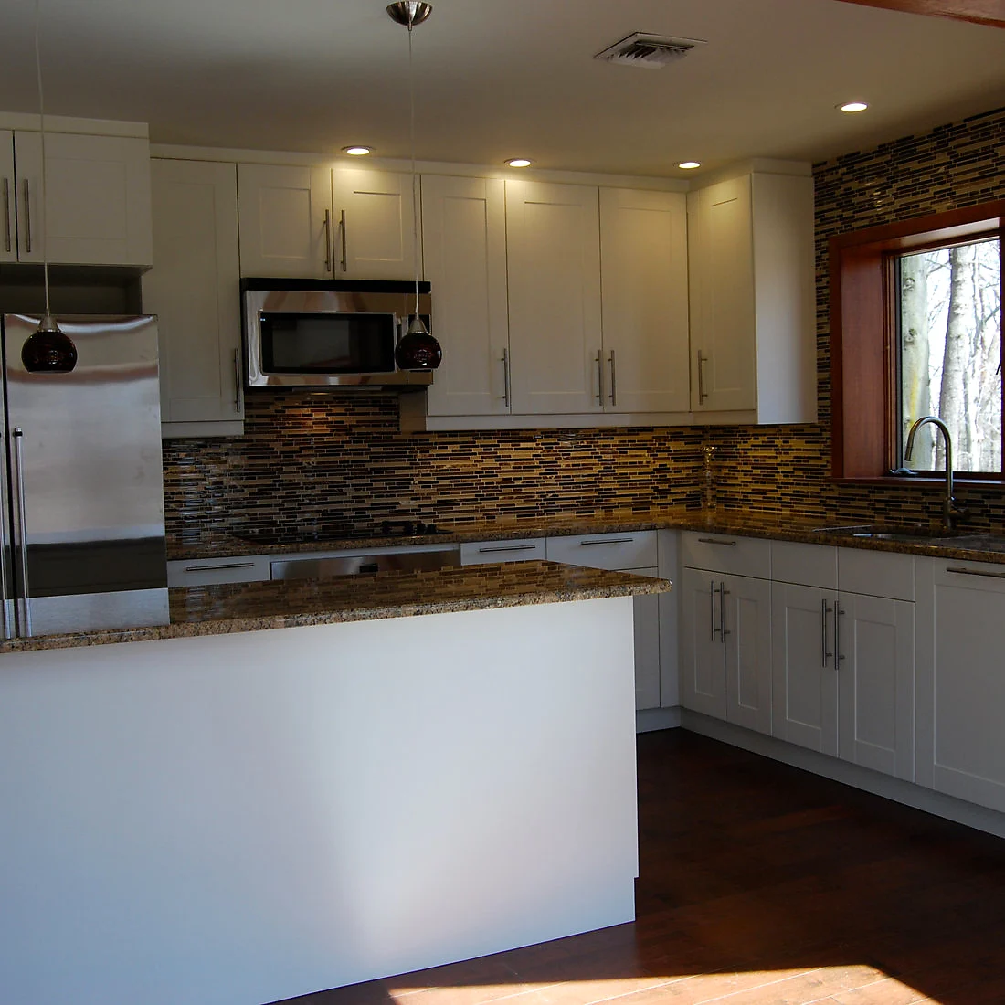 The same white kitchen from the sink, glass mosaic tile running to the ceiling