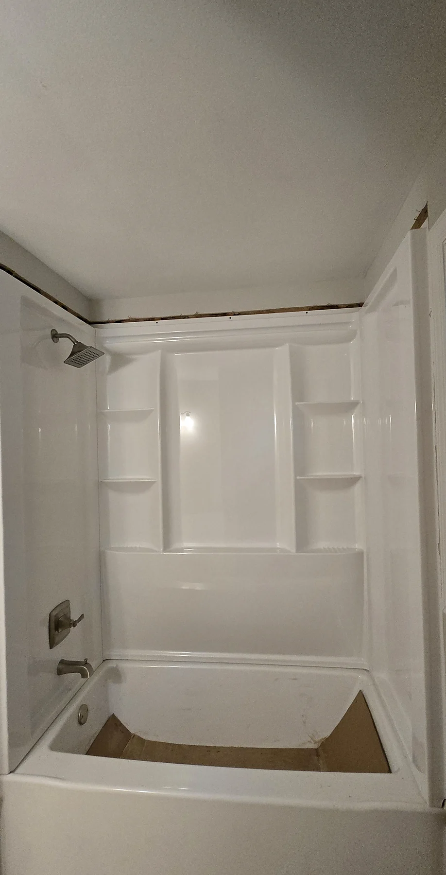 Finished white fiberglass tub and shower surround with a built-in shelf and new fixtures