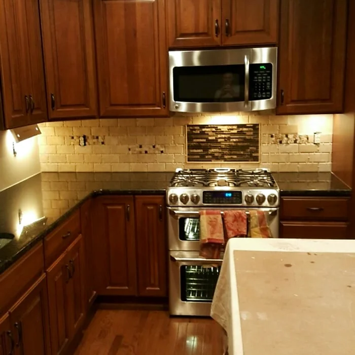 Cherry kitchen with a travertine-tile backsplash, double oven range and stainless hood